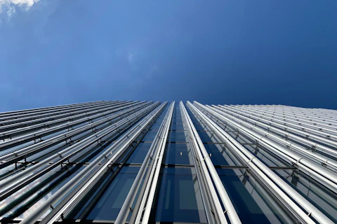 Fotografowany od dołu wysoki, solidny budynek, z widocznym nad nim niebieskim niebem.